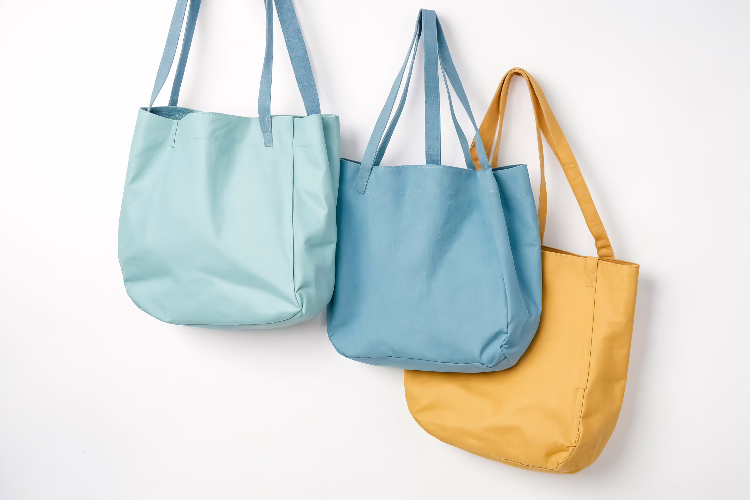 Three Stylish Tote Bags Hanging on a White Wall